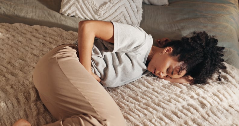 Woman lying in bed, cramps after masturbating.