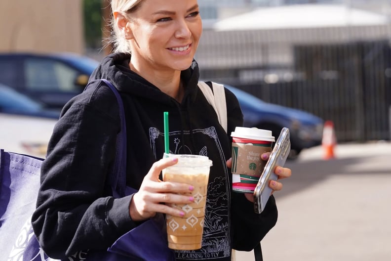 Ariana Madix carrying two Starbucks drinks and two tote bags